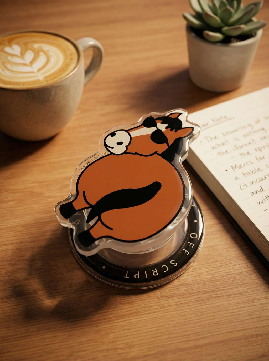 OFF SCRIPT Flattery Little Horse MagSafe phone grip lying on wooden desk beside a latte and notebook, lifestyle flat lay